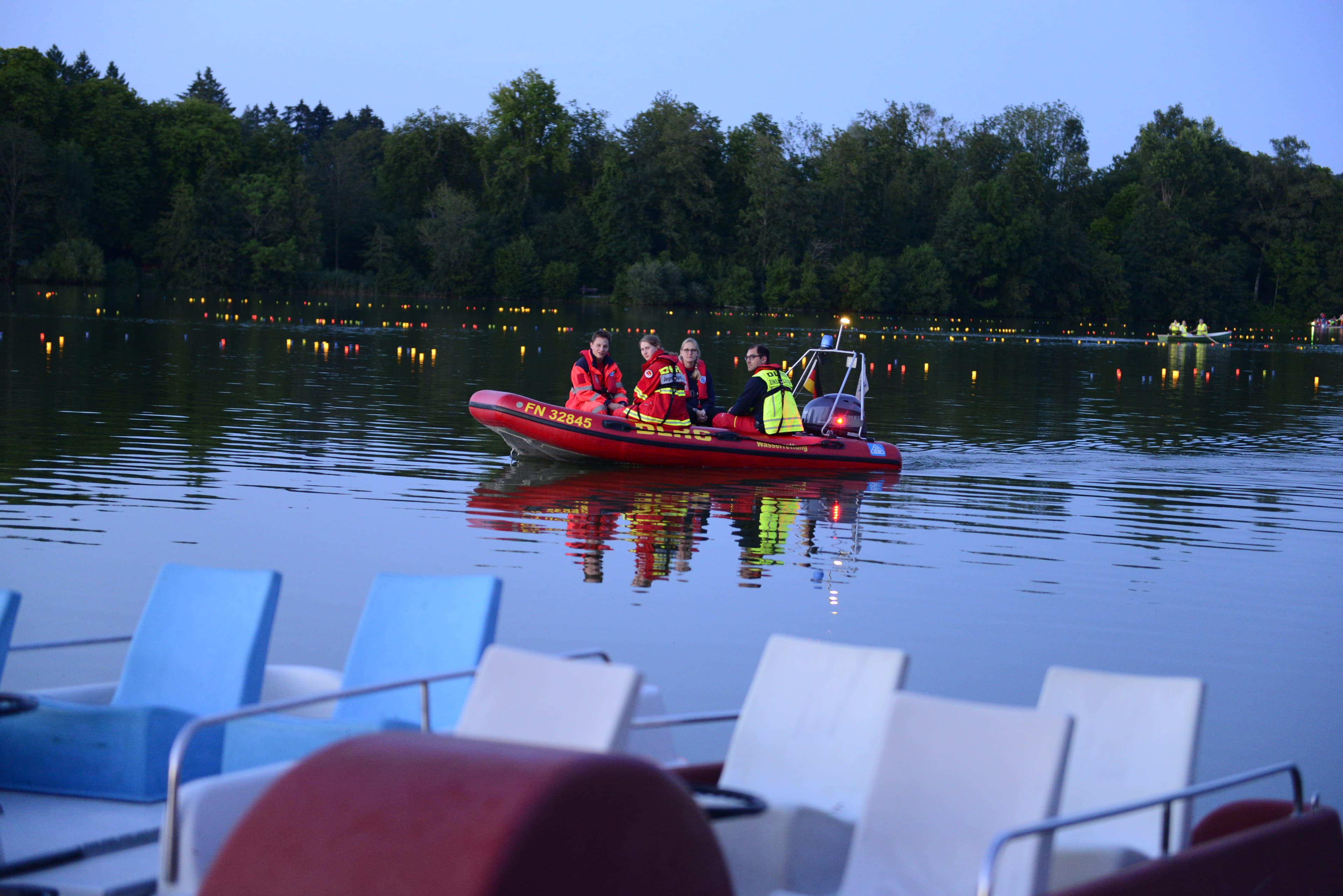 DLRG-Einsatzboot mit Besatzung auf dem beleuchteten Stadtsee in Bad Waldsee
