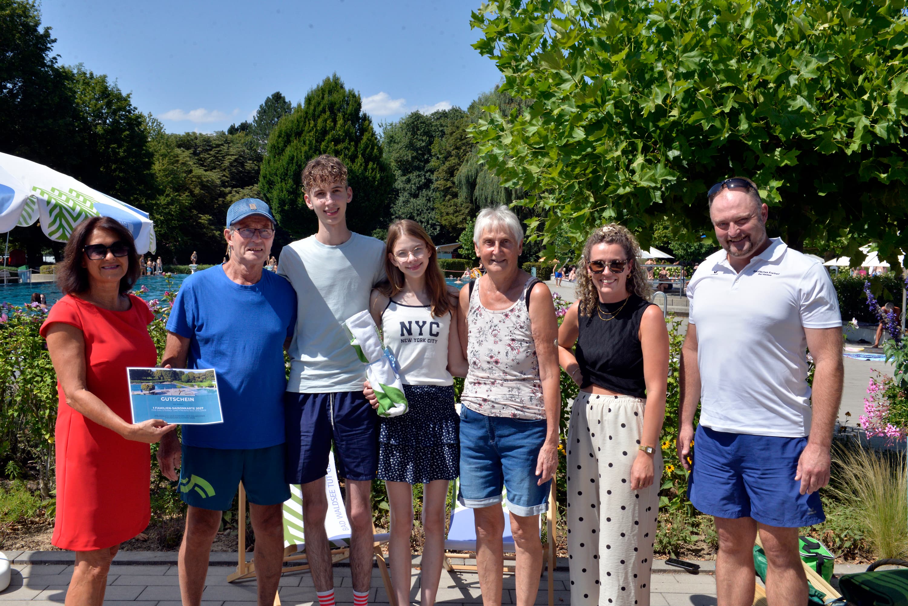Bürgermeisterin Monika Ludy (links) gratulierte auch im Namen von Oberbürgermeister Matthias Henne gemeinsam mit Freibadleiter Marc Steiner (rechts) und Sarah Baur (2. von rechts) der Familie Thoma zum 100.000. Badegast der Freibadsaison 2026. Als Erinnerung gab es eine Familien-Saisonkarte für 2027 sowie ein Bad-Waldsee-Badetuch.