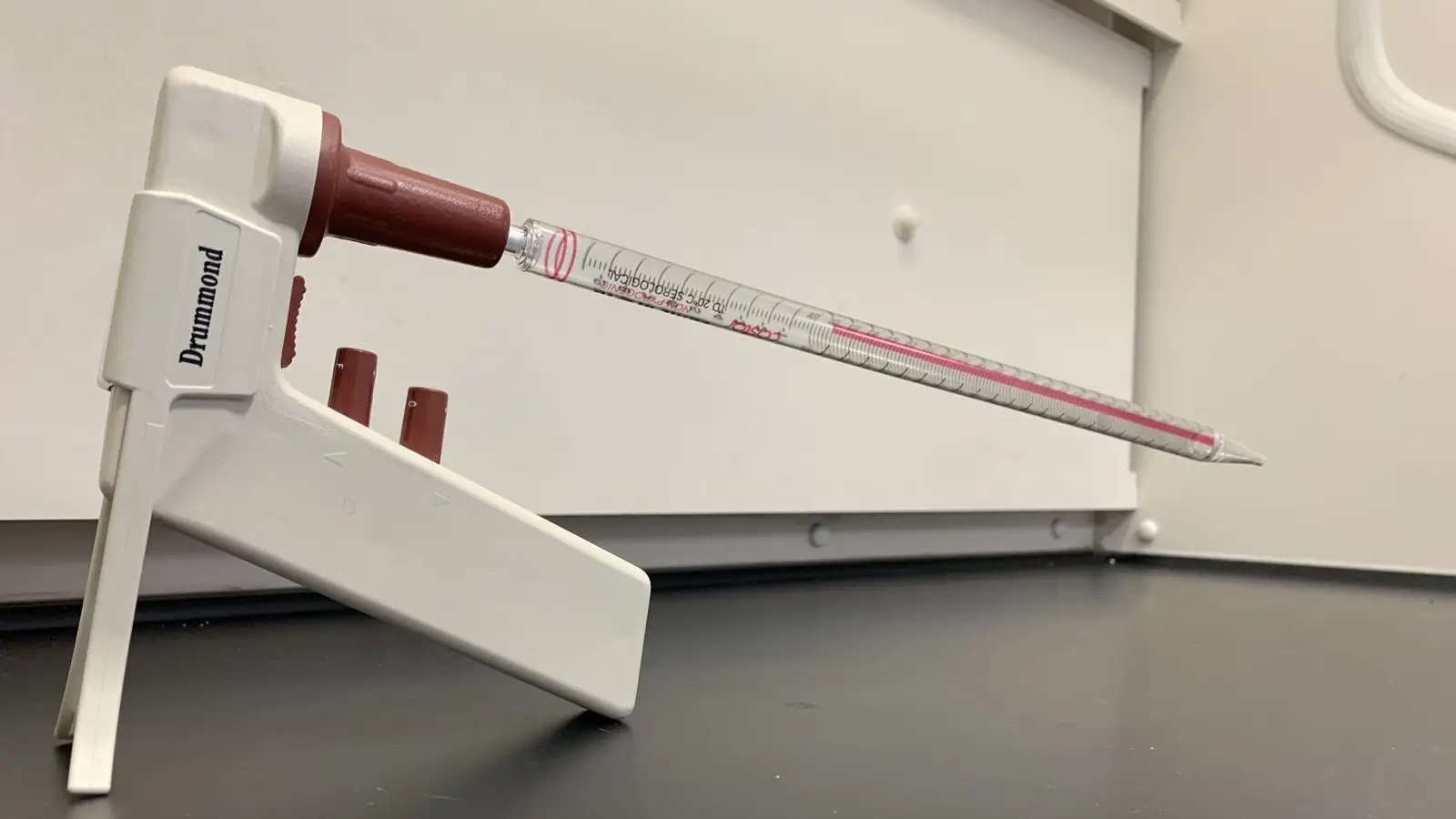 Pipettierhilfe mit gläserner Pipette auf einem Laborständer.